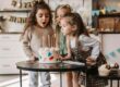 Girls blowing candles from birthday cake on table