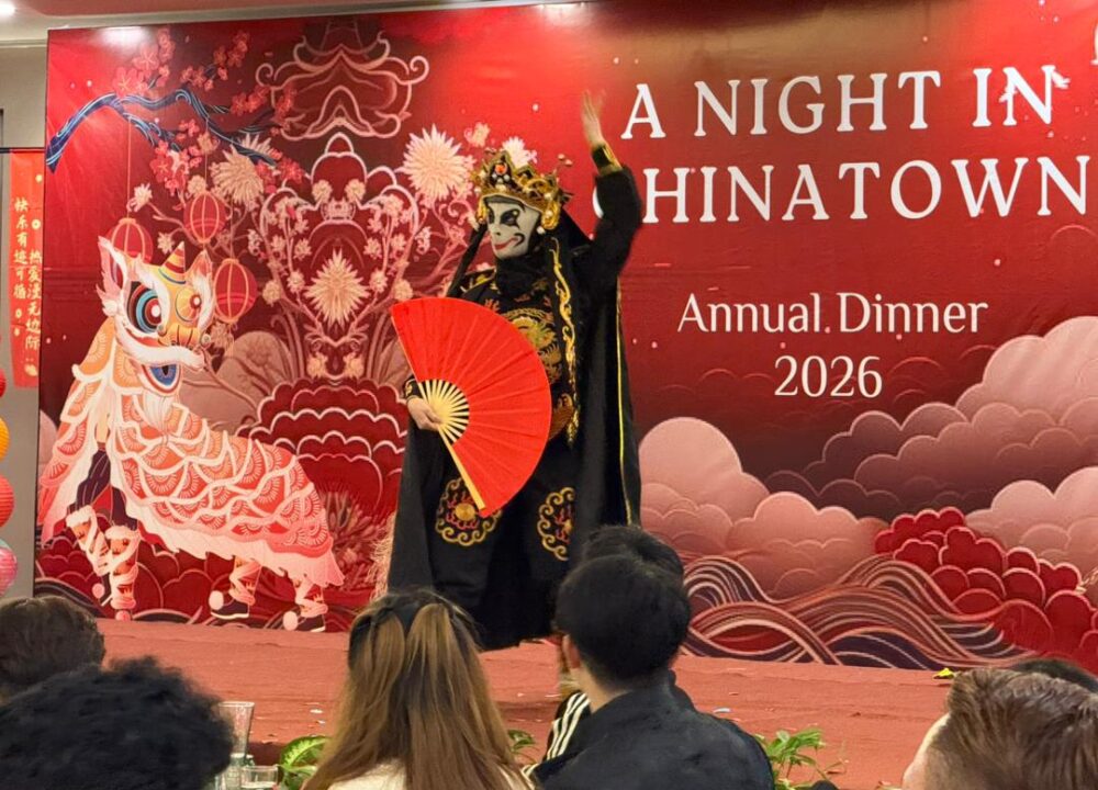 Bian Lian mask changing artist performing live at a 2026 corporate event in traditional Chinese costume