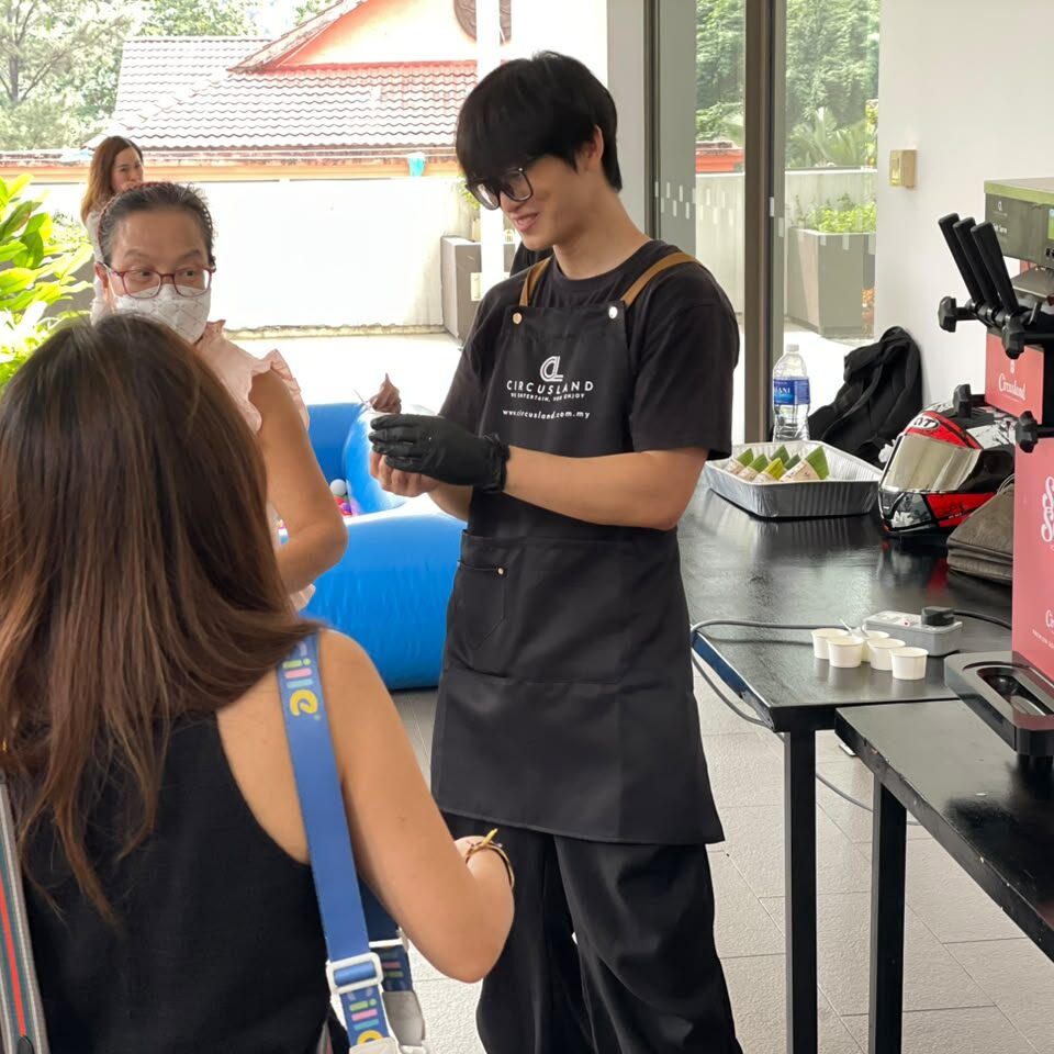 Smiling child holding vanilla soft serve ice cream cone served by Circusland staff at family-friendly event with ball pit activity area